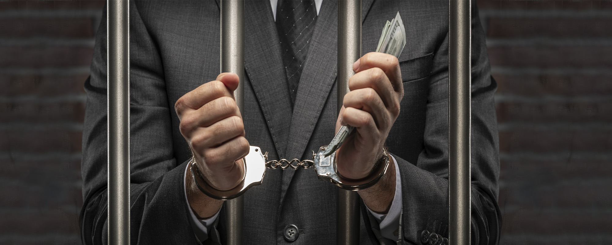 man holding bills of money with a handcuff in a jail