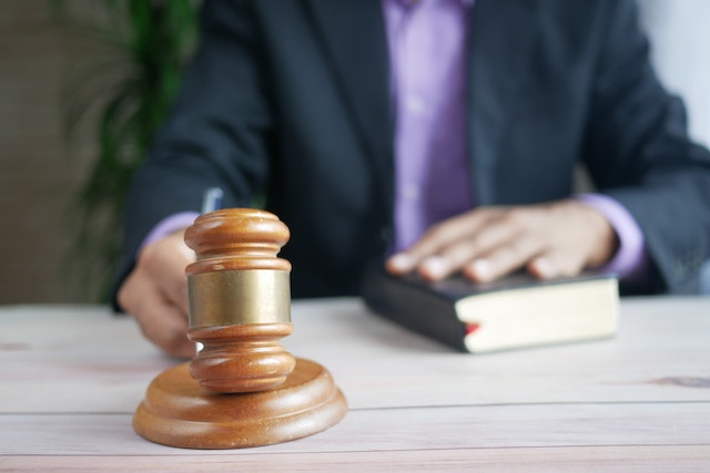 man holding gavel with hand on bible